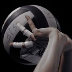 a person holding a volleyball ball with their hands and fingers in front of the ball