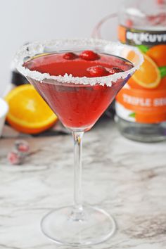 a red cocktail in a martini glass with powdered sugar on the rim