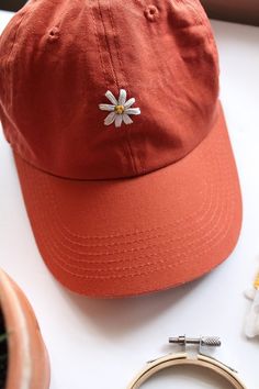 a red hat with a white flower on it sitting next to a pair of scissors