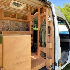 the interior of a van with its doors open and clothes hanging on shelves in the back