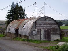 an old run down barn sits on the side of a road