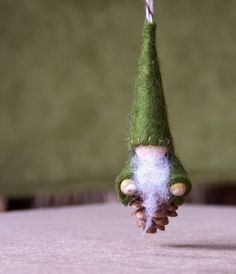 a small green gnome's head hanging from a string