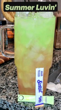 a green drink in a glass next to a tube of toothpaste on a counter