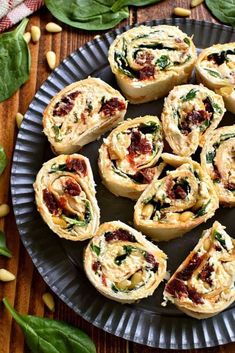 a plate filled with mini pizzas on top of a wooden table next to green leaves