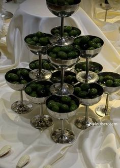 there are many glasses with olives in them on the table