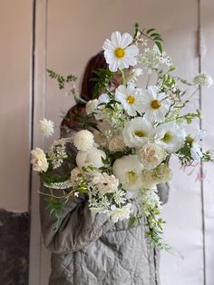 a woman holding a bouquet of white flowers