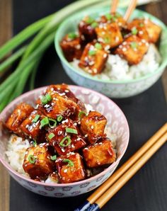 two bowls filled with food and chopsticks next to each other