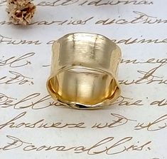 a gold ring sitting on top of a piece of paper with writing in the background