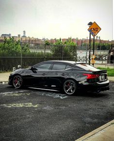 a black car parked in a parking lot next to a street sign