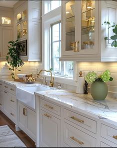 a white kitchen with marble counter tops and gold trimmings on the cabinet doors