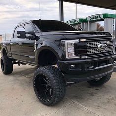 a black truck parked in front of a gas station