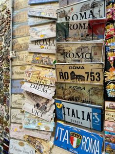 there are many different license plates on this street sign wall that is stacked high up