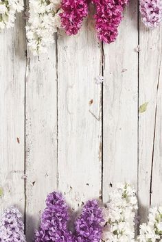 purple and white flowers are arranged in the shape of a heart on a wooden background