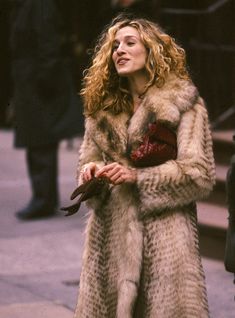 a woman in a fur coat is standing on the street and talking to someone behind her