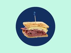 a cut in half sandwich with meat and cheese on blue circle frame against a light green background