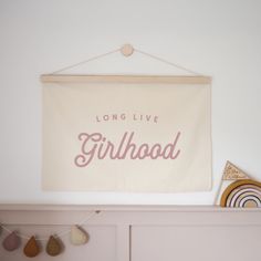 there is a sign that says long live girlhood hanging on the wall above a dresser