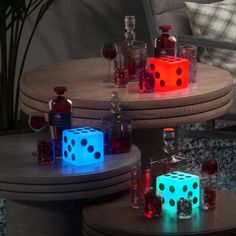 three lit up dices sitting on top of a table next to bottles and glasses