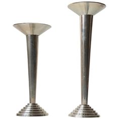 two metal candlesticks sitting side by side on a white background, one is turned upside down