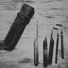 the tools are laid out on the wooden table next to the leather sheath and knife