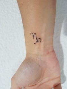 a woman's wrist with a small zodiac sign tattoo on the left side of her hand