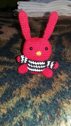 a crocheted red bunny holding a tennis racquet on top of a bed