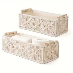 two white wicker baskets with handles on each side and one holding toilet paper rolls