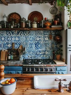 a kitchen with blue and white tiles on the wall, sink, stove top and cabinets