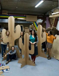 some people are posing in front of cardboard cactus sculptures that look like they have been cut out