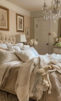 a bedroom with a bed, chandelier and pictures on the wall