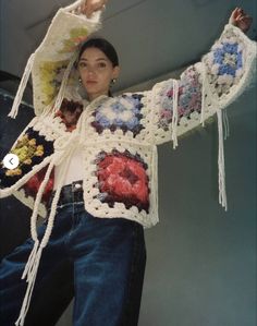 a woman is wearing a crocheted jacket with fringes and flowers on it