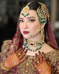 a woman with henna on her face and hands in front of her face, wearing an elaborate head piece