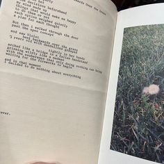 an open book with writing on it in the middle of someone's hand and grass