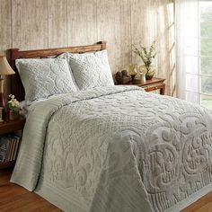 a bed with white comforter and pillows in a room next to a wooden headboard