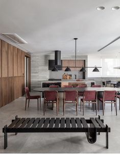 an open kitchen and dining room area in a modern home with concrete flooring, wood panel