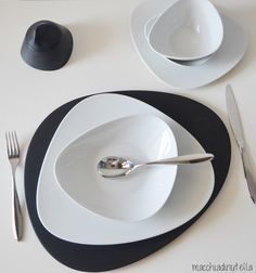 the table is set with black and white plates, silverware and utensils