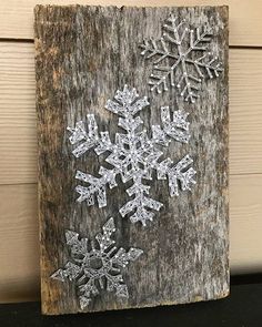 a snowflake is hanging on the side of a wooden sign that has been painted white