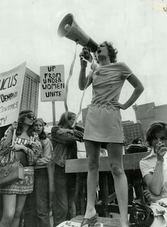 a woman speaking into a megaphone while standing in front of a group of people