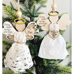 two wooden angel ornaments hanging from a christmas tree