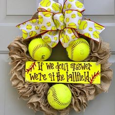 a wreath that has softballs on it with a sign saying if we don't answer, we're at the ballfield