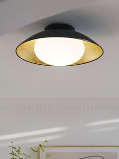 a black and gold light hanging from the ceiling in a living room with white walls