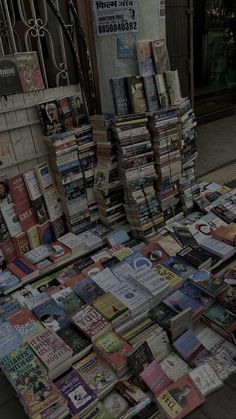 many books are stacked up on the sidewalk