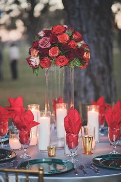 a table with candles and flowers in vases next to each other on it's centerpiece