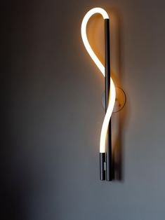 a wall mounted light with a curved tube attached to it's side and an arm that is lit up