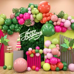 a birthday backdrop with balloons and greenery