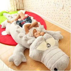 a baby laying on top of a stuffed animal in a room with two other stuffed animals