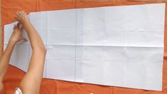 two people are making a large piece of paper with scissors and tape on the wall