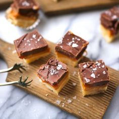 four pieces of dessert sitting on top of a wooden cutting board next to a spoon