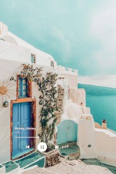 a white building with blue doors and windows overlooking the ocean