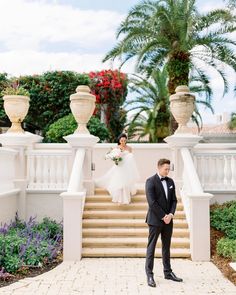 a bride and groom standing on the steps of their wedding venue in front of palm trees