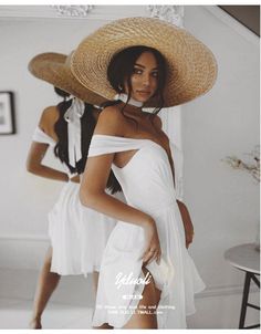 a woman in a white dress and straw hat posing for the camera with another woman behind her